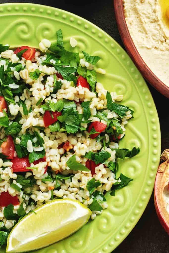 Jordanian dish tabbouleh on a green plate dishes on a dark rustic background.