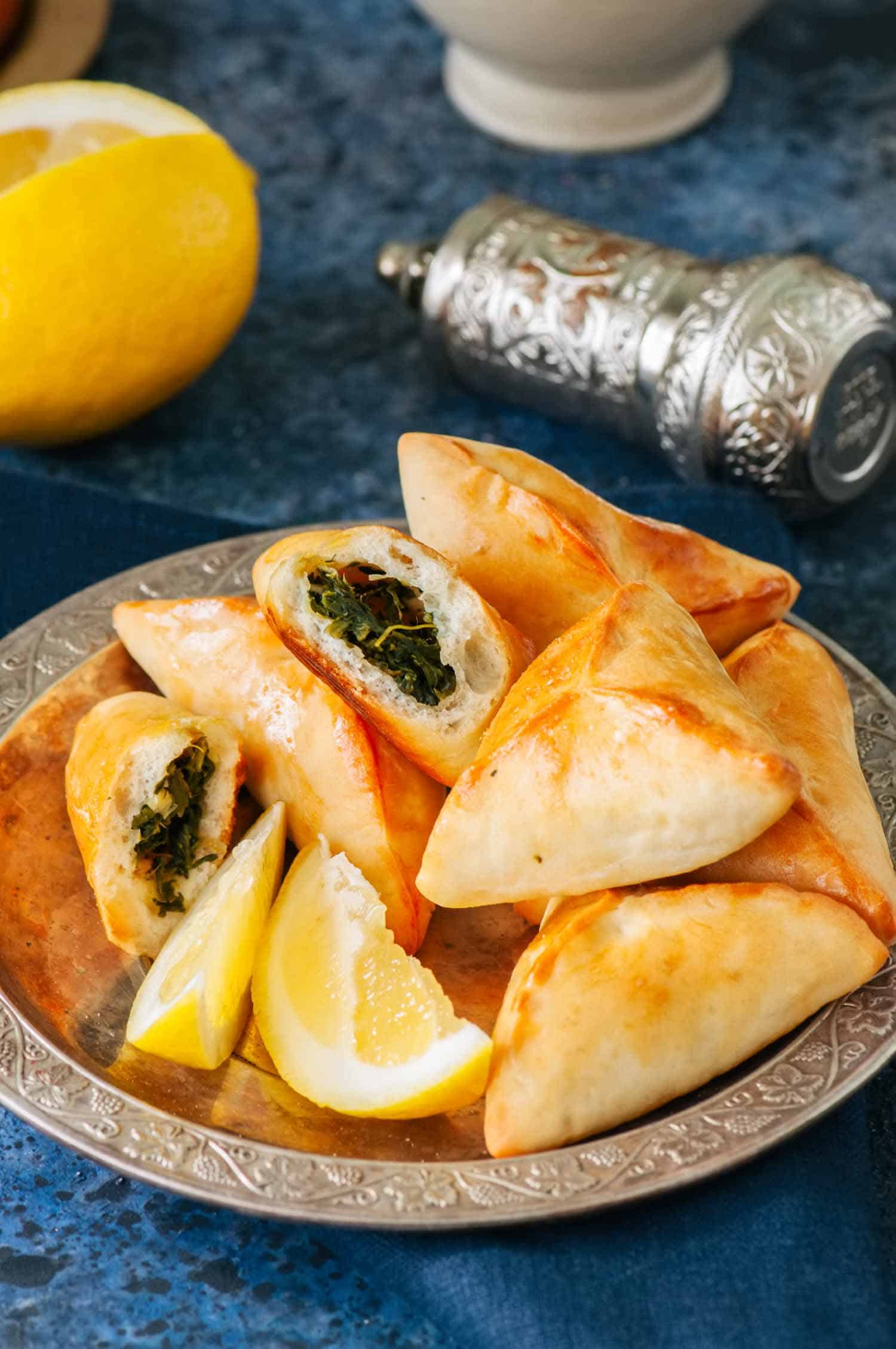 Arabic and middle eastern food concept. Fatayer sabanekh - traditional arabic spinach triangle hand pies on a blue stone background.