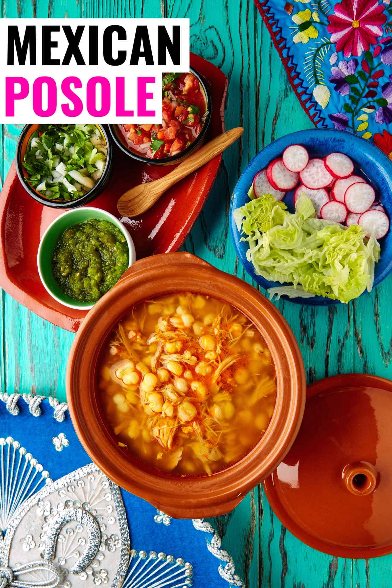 Mexican stew called pozole on a bright background with all of the garnishes like radish, lettuce and salsa