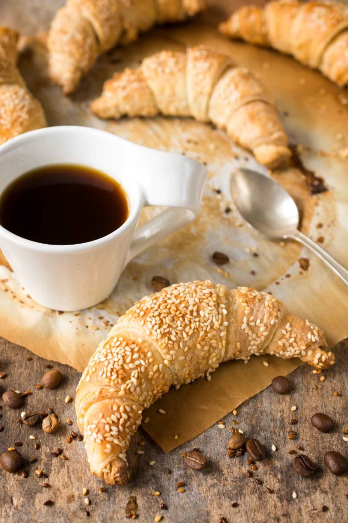 Traditional fresh baked Danish croissants and cup of black coffee.Selective focus on the front croissant