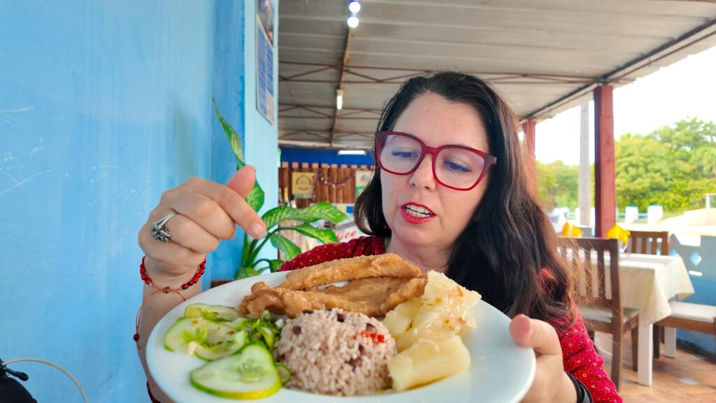 Ayngelina pointing at a plate of fried fish with coconut rice and yuca at a restaurant in Varadero Cuba