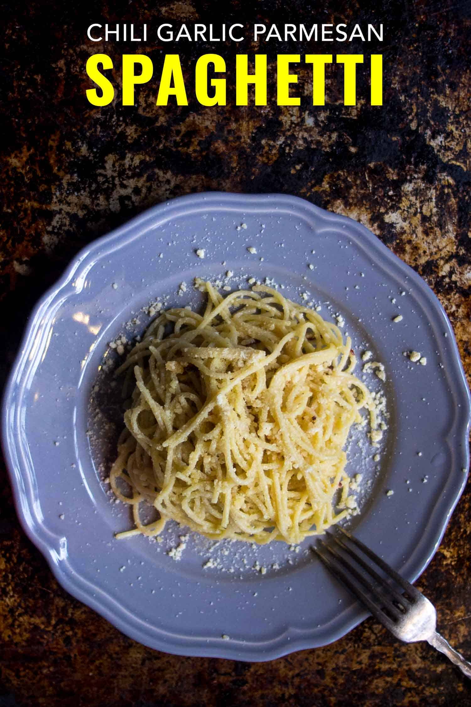 Chili garlic parmesan spaghetti on a blue plate on a rustic background.