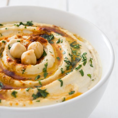 Hummus in a white bowl on a white background