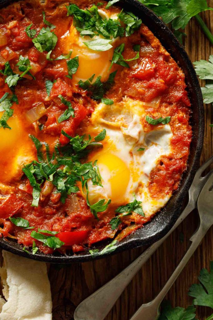 Traditional Jerusalem food shakshuka, a tomato and eggs dish in a cast iron pan.
