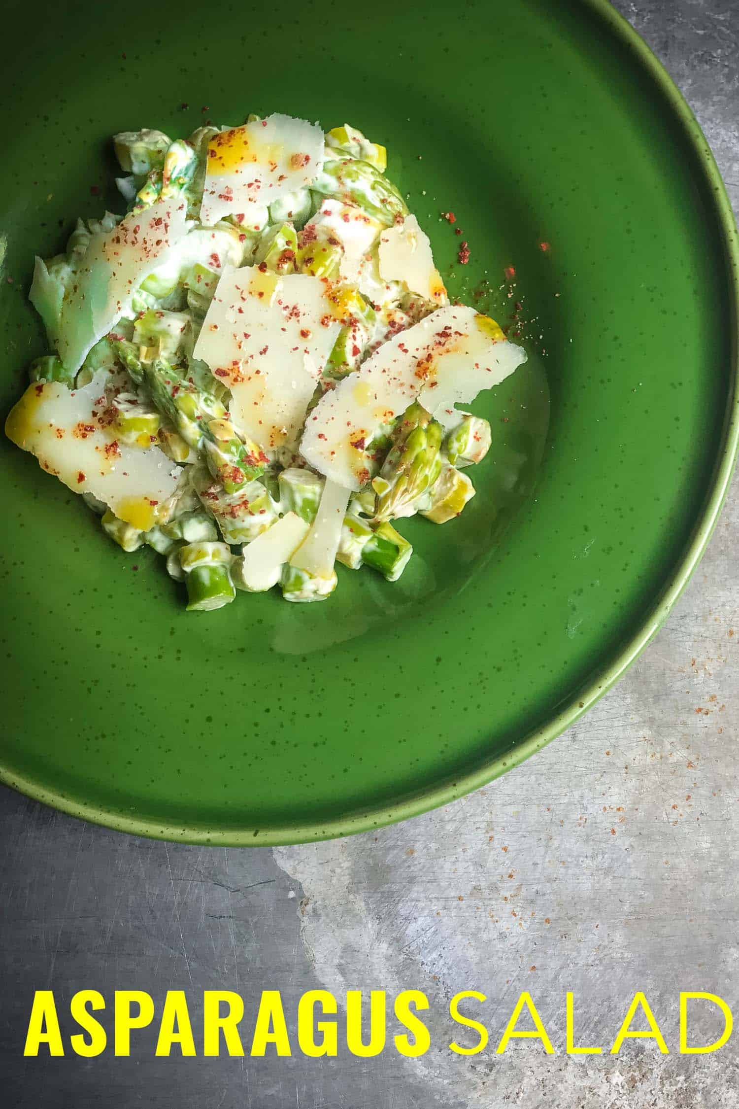 asparagus parmesan salad on a green plate and silver background