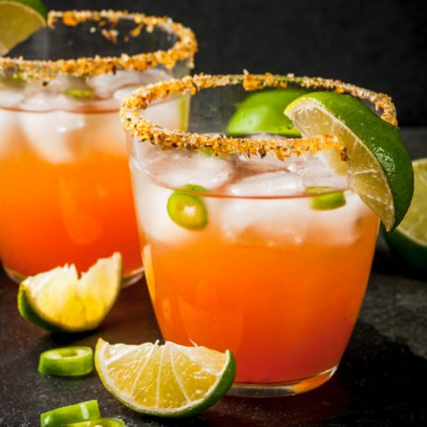 Mexican Micheladas, a beer cocktail garnished with lime on a black background.