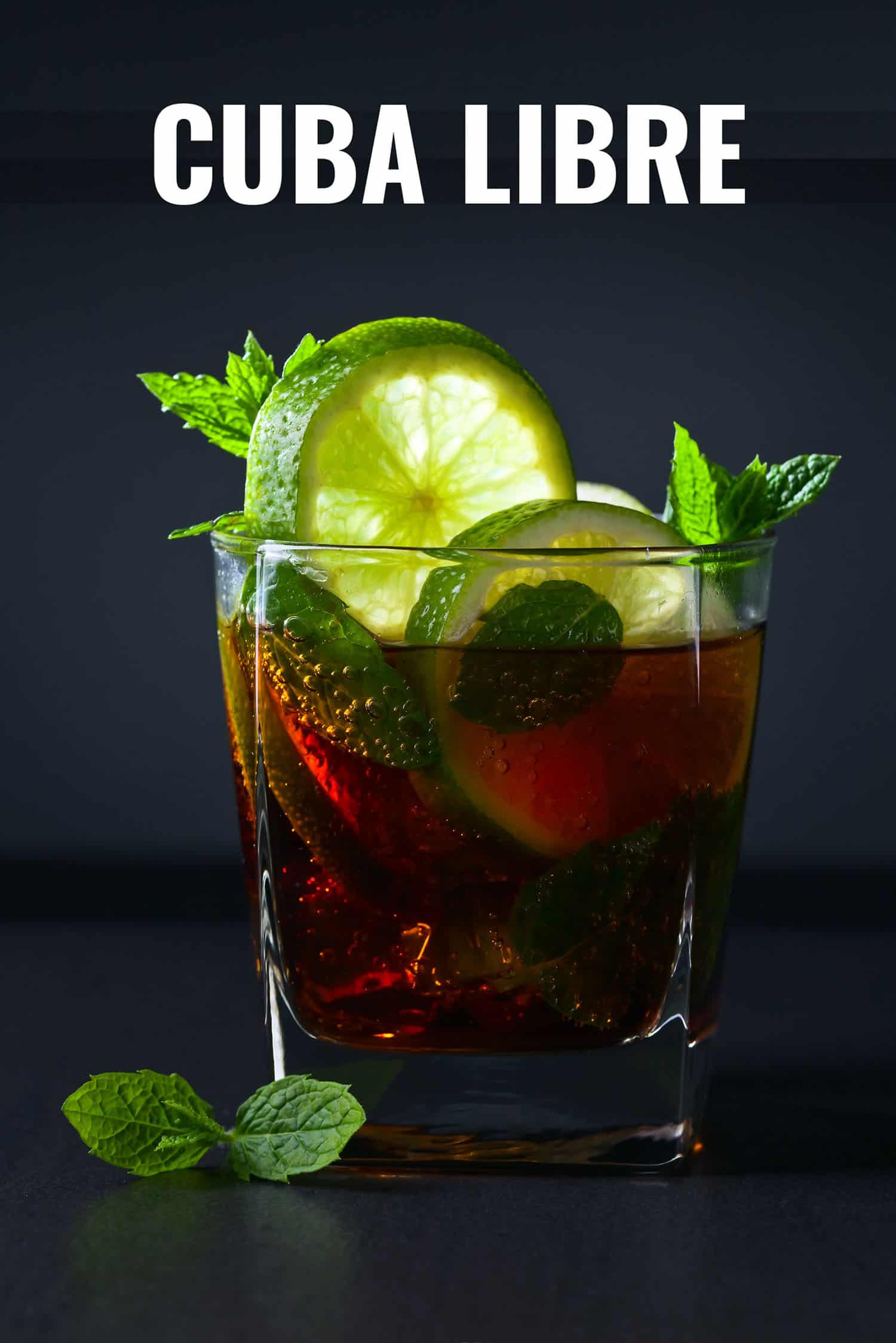 Cuba libre cocktail in a glass garnished with lime on a black background.