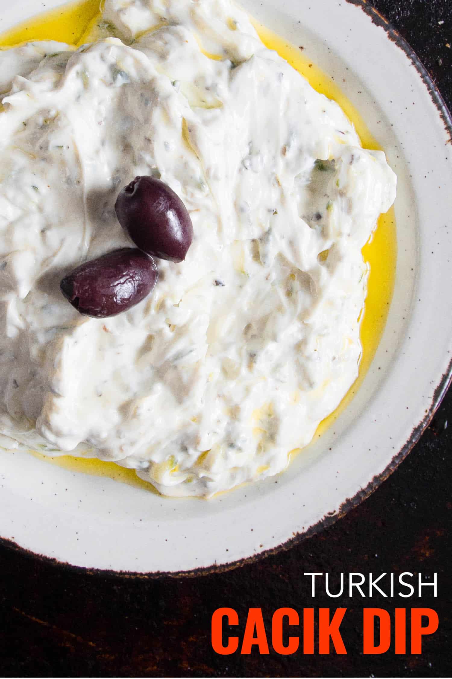 Turkish cucumber yogurt dip on a white plate and black background