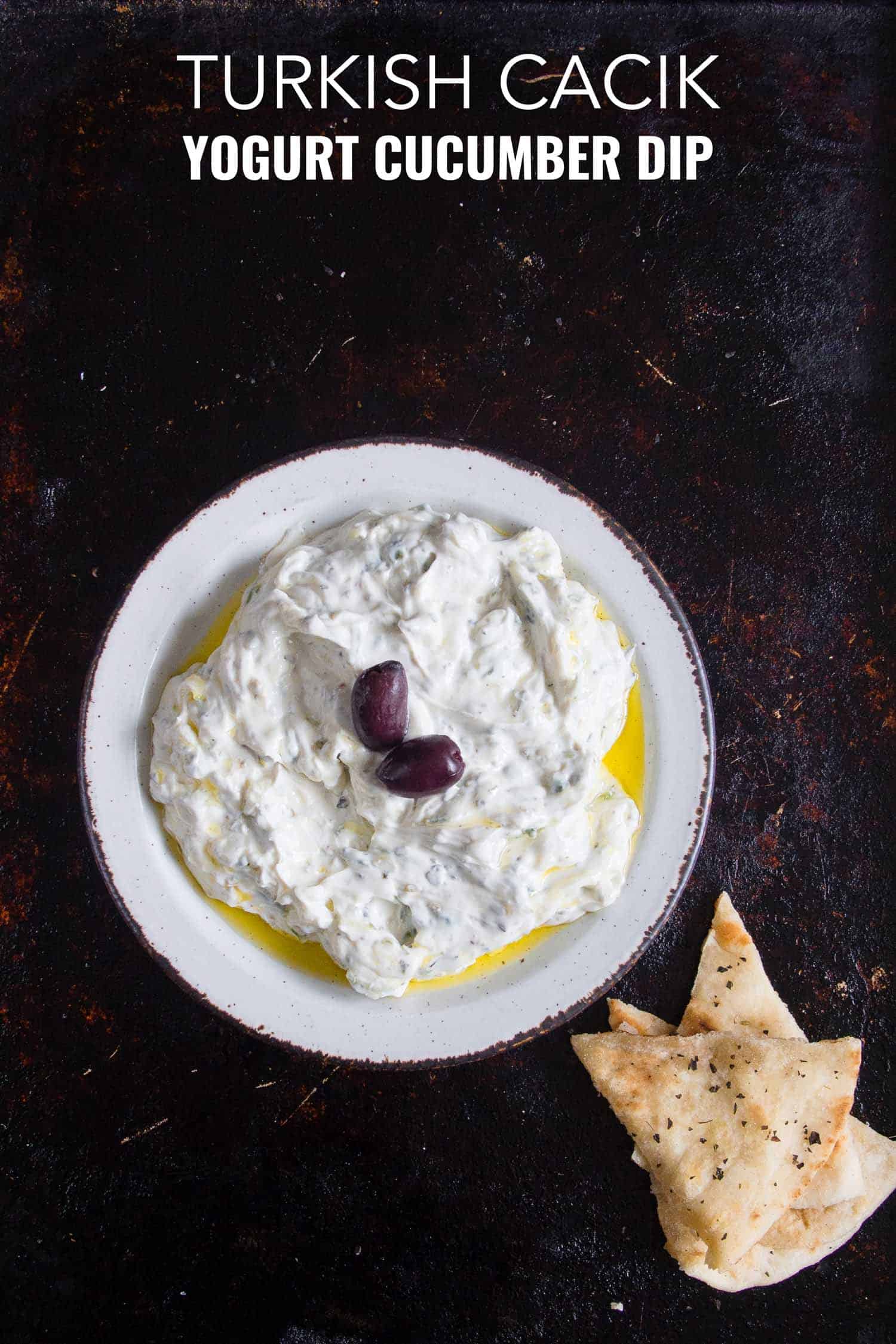 Turkish cucumber yogurt dip on a white plate and black background