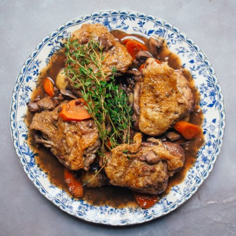 Coq au Vin on a plate on a grey background