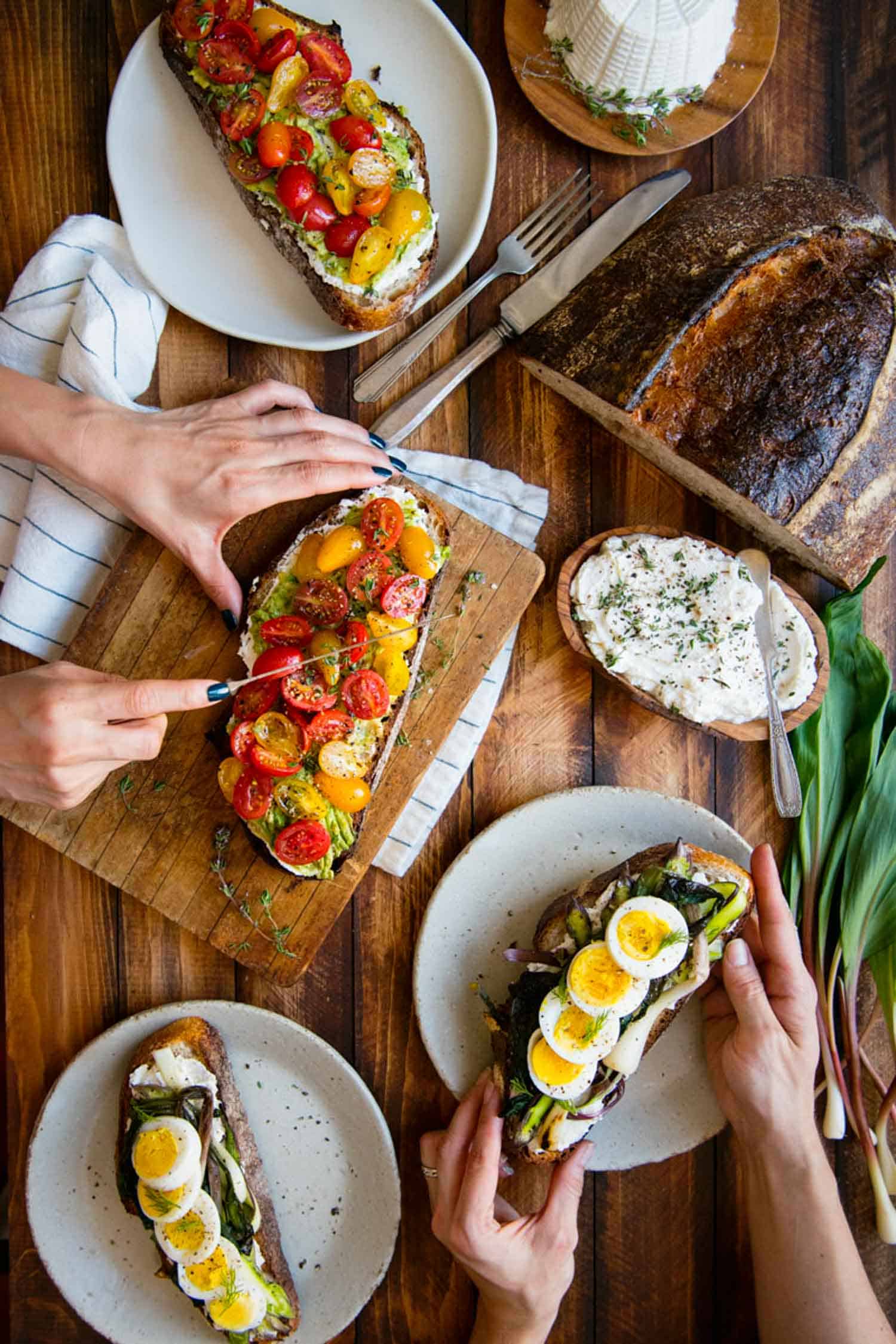 Tabletop shot of people eating open faced sandwiches with ramps.