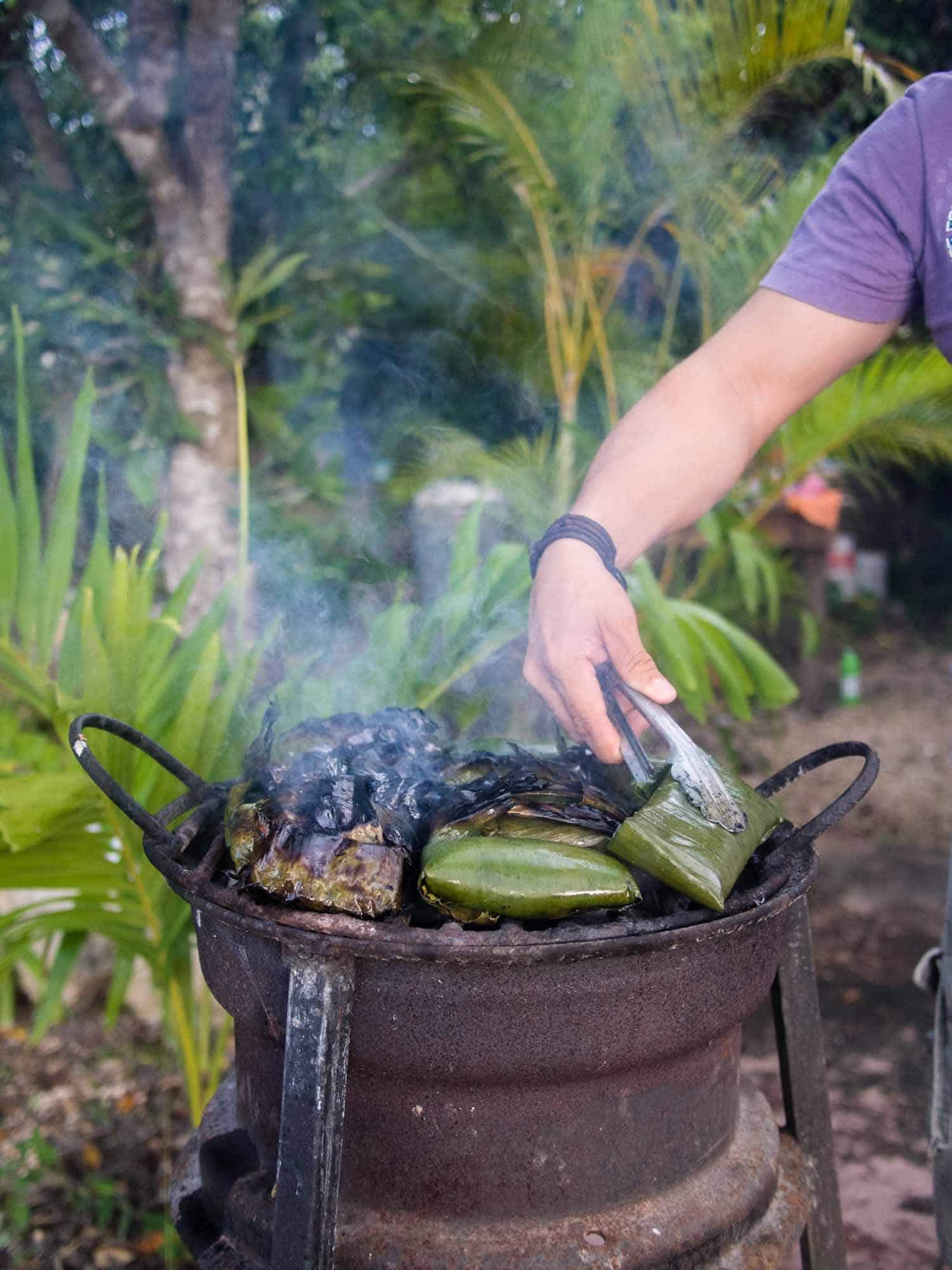 Grilling tamales in banana leaves.