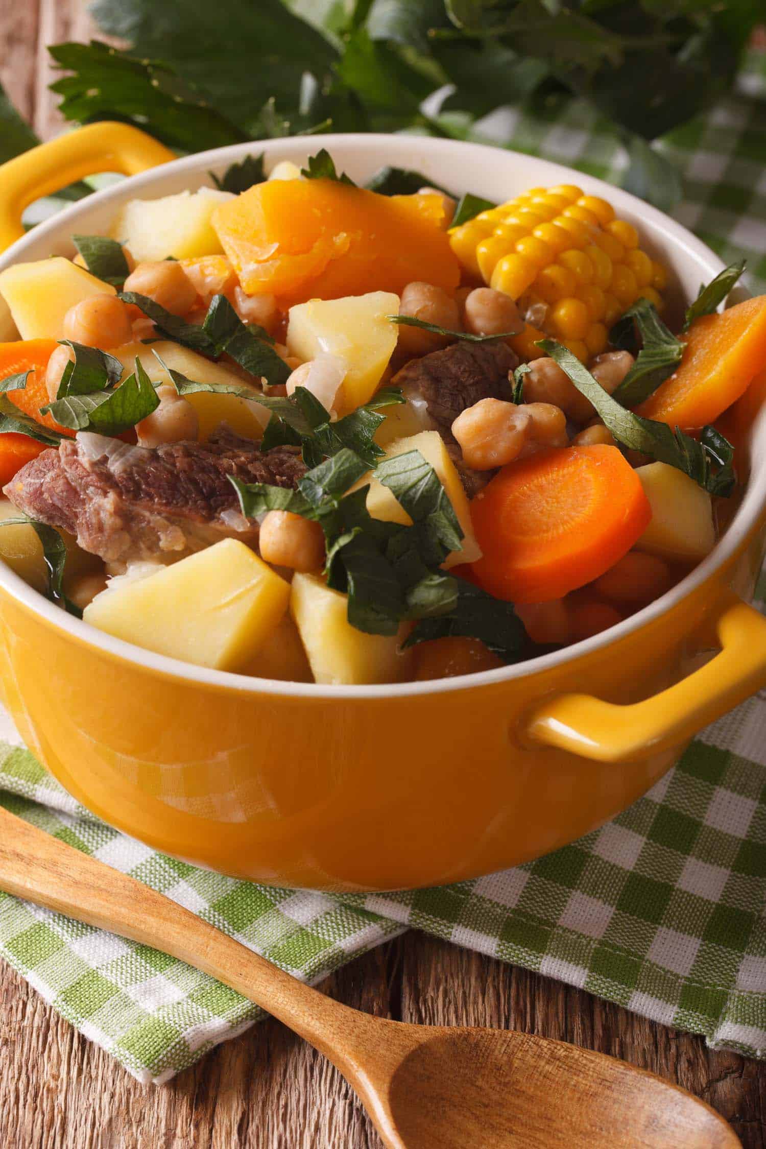 South American cuisine: thick soup Pouchero close-up in a pot on the table. Vertical