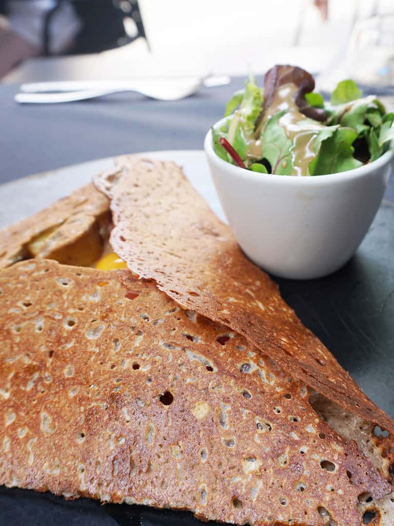 Traditional French galette with bowl of salad on the side.