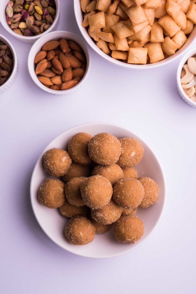 homemade tasty Diwali food or Diwali snacks or Diwali sweets like rava laddu, chakli, sev, shankar pale and chivda or chiwada with dry fruits in white bowls, favourite indian diwali recipe