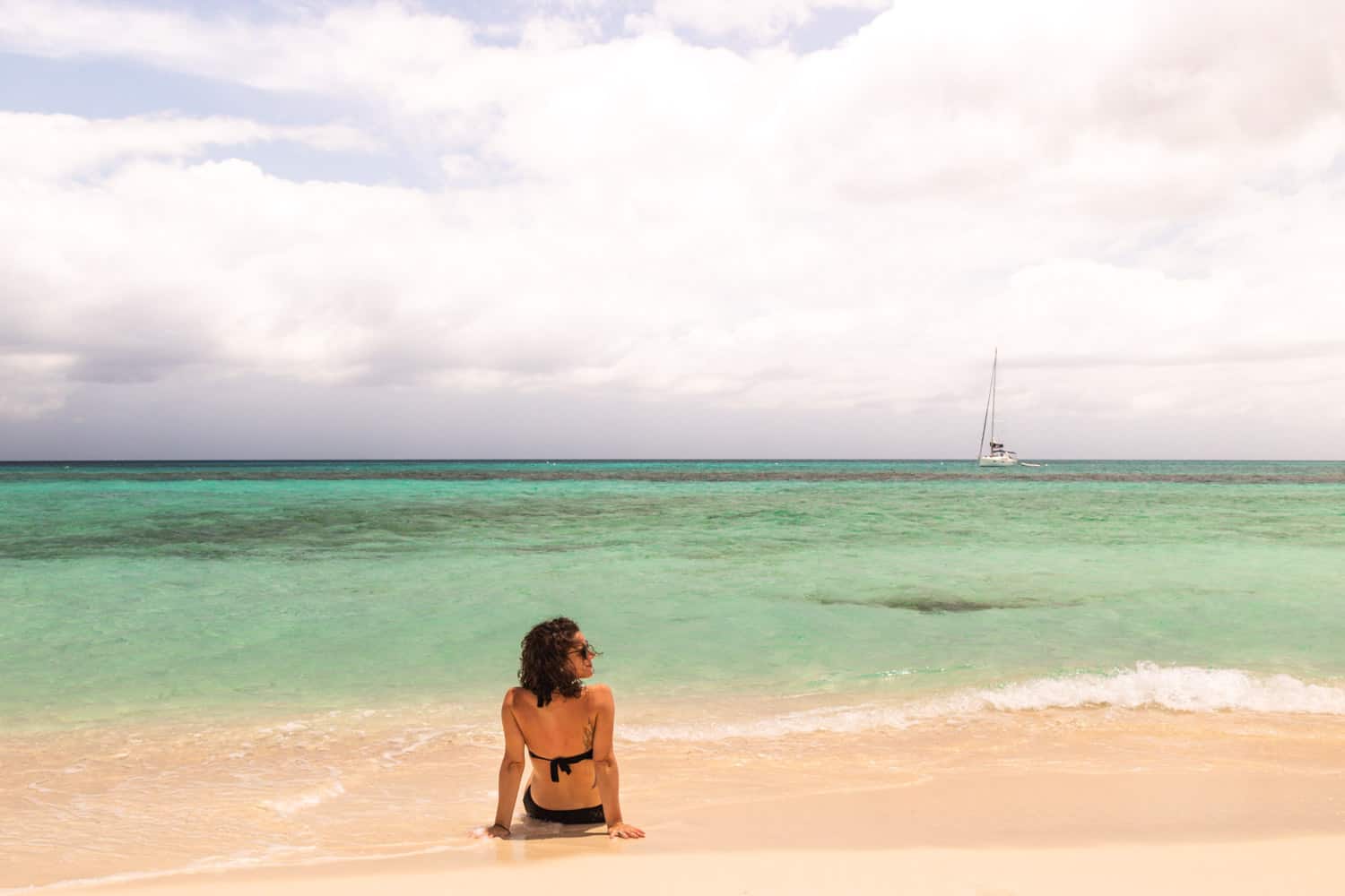 Sandy Island beach in Anguilla with a woman sitting on the beach