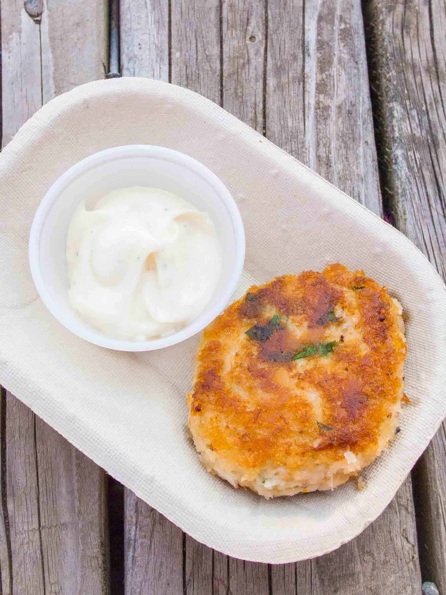 Traditional Nova Scotia food, fish cakes in a take out container on a unfinished picnic table.