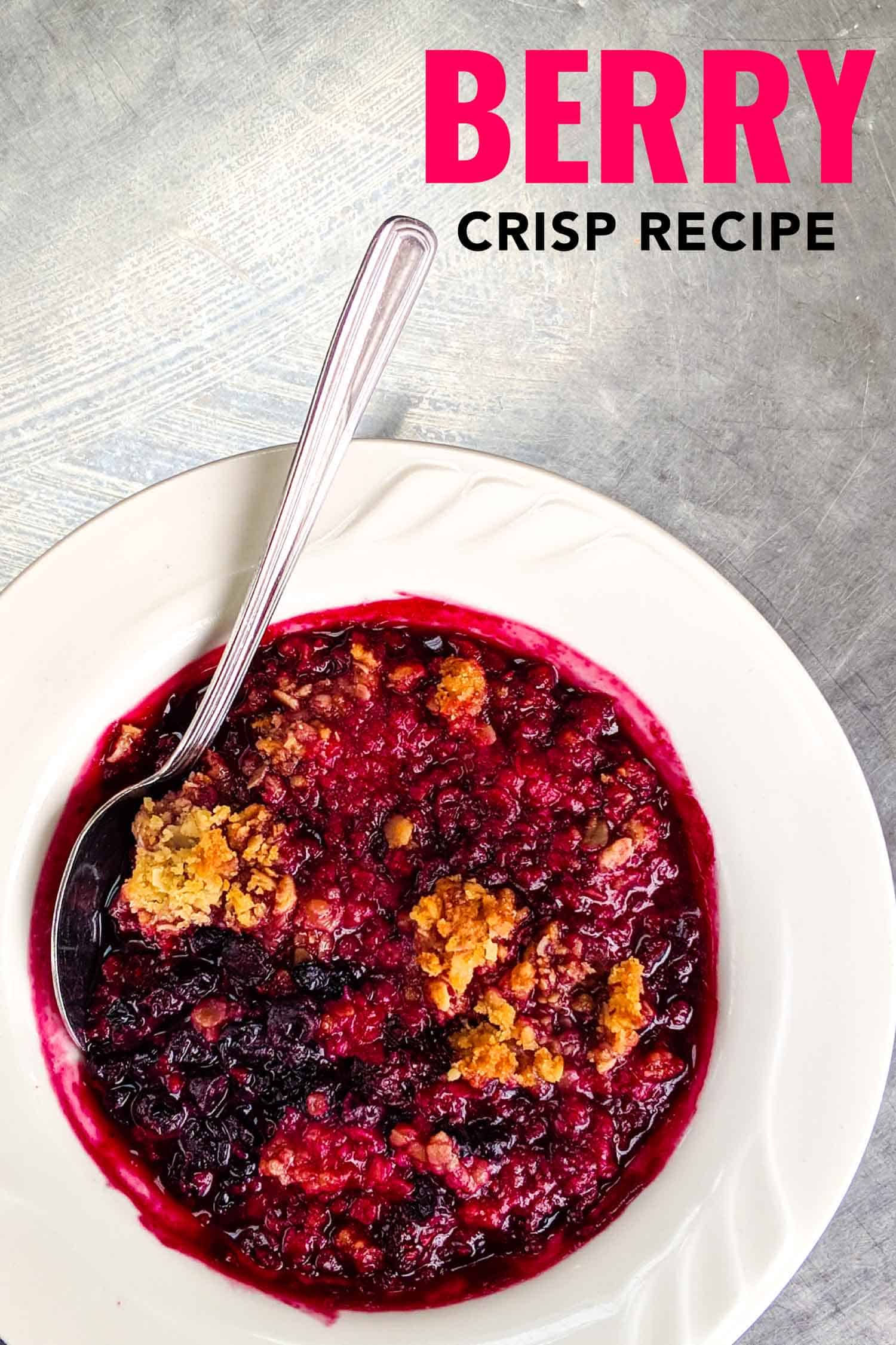 Mixed berry crisp recipe in white bowl on silver background, a classic Nova Scotian dessert.