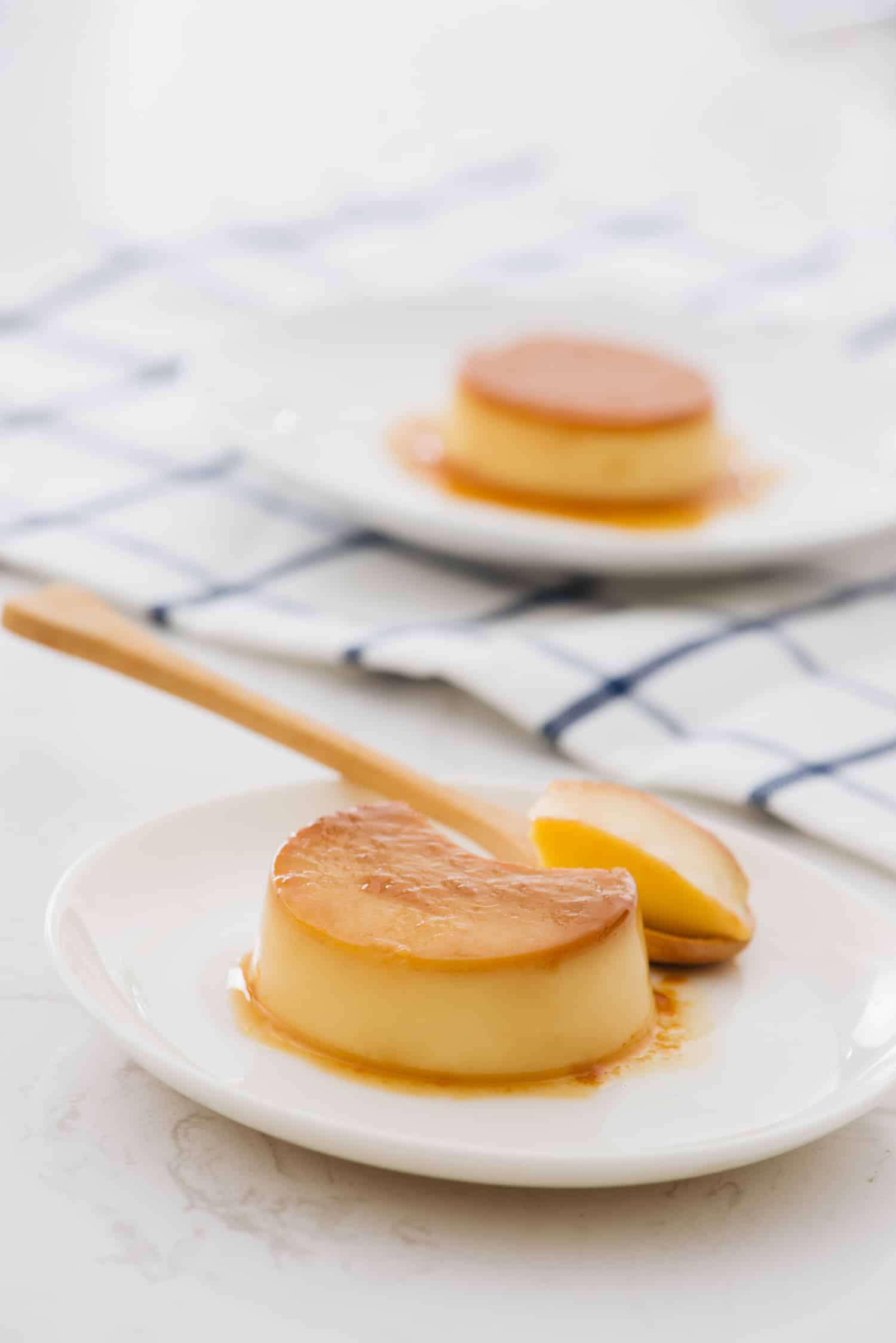 Individual Cuban flan with Spoon takes a piece of homemade custard, isolated on white