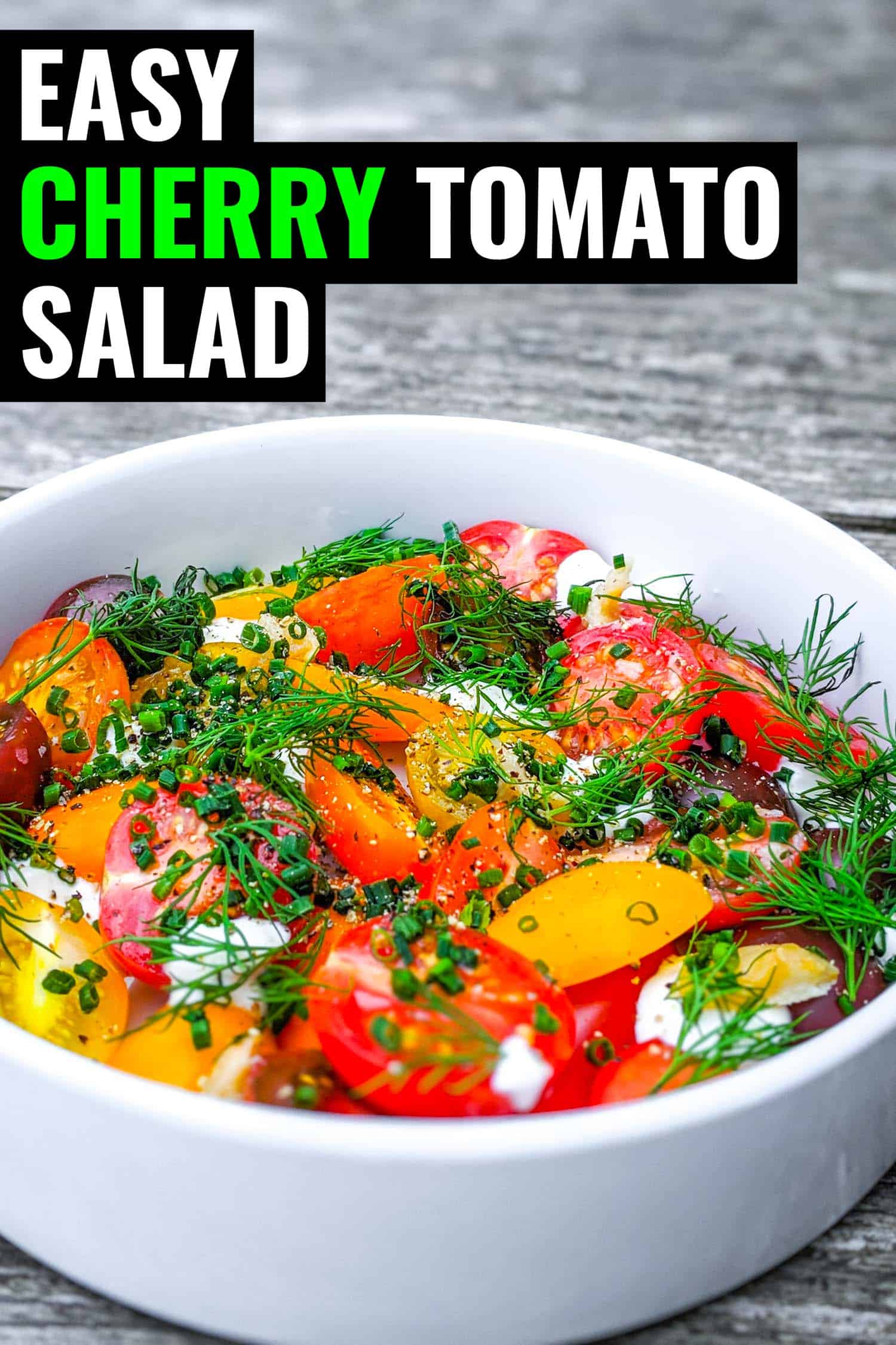 Fresh cherry tomato salad with herbs and creme fraiche in white bowl on grey wood background