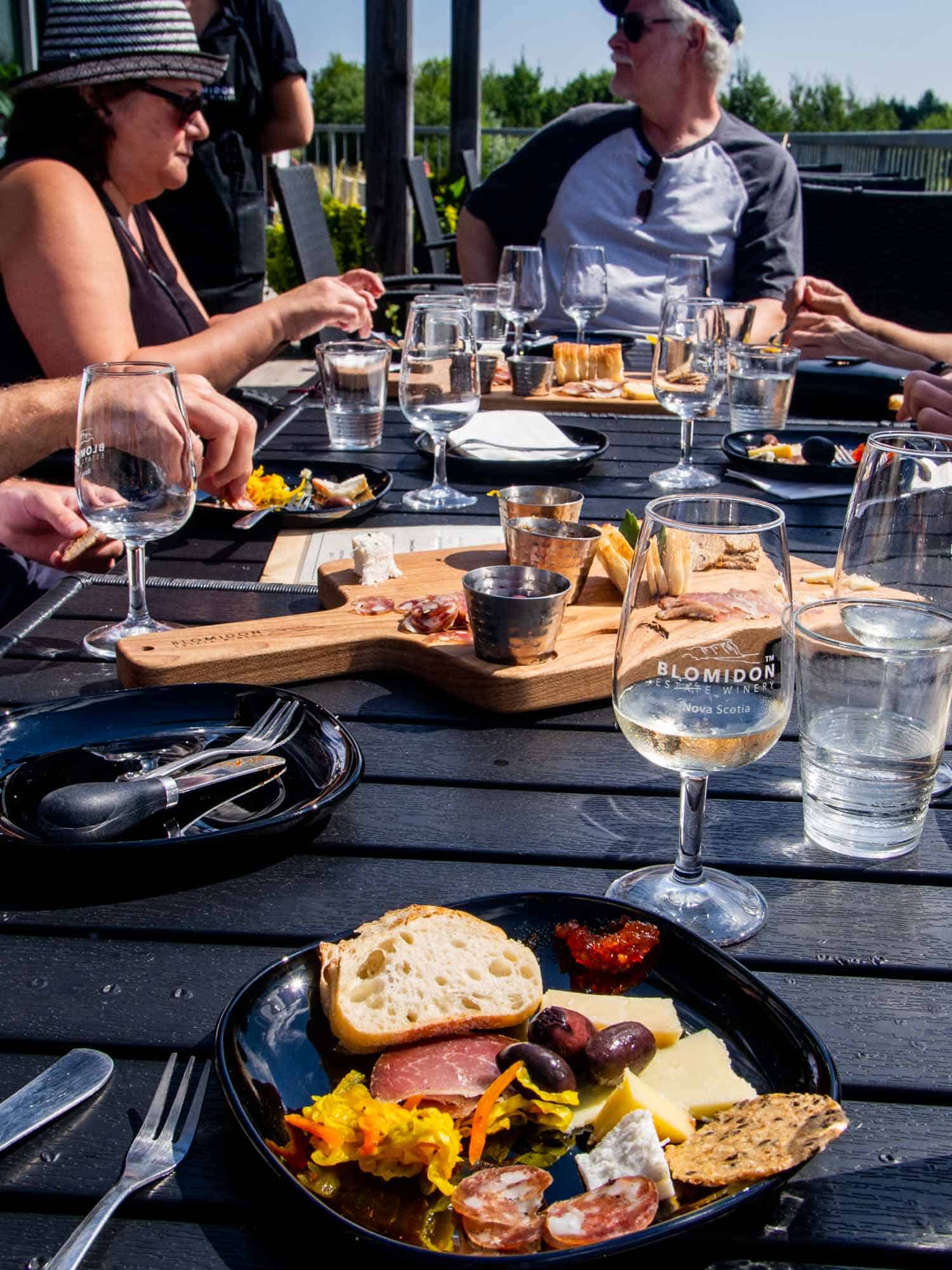 Blomidon Estate Winery in Canning Nova Scotia, people at table drinking Nova Scotia wine and eating charcuterie.