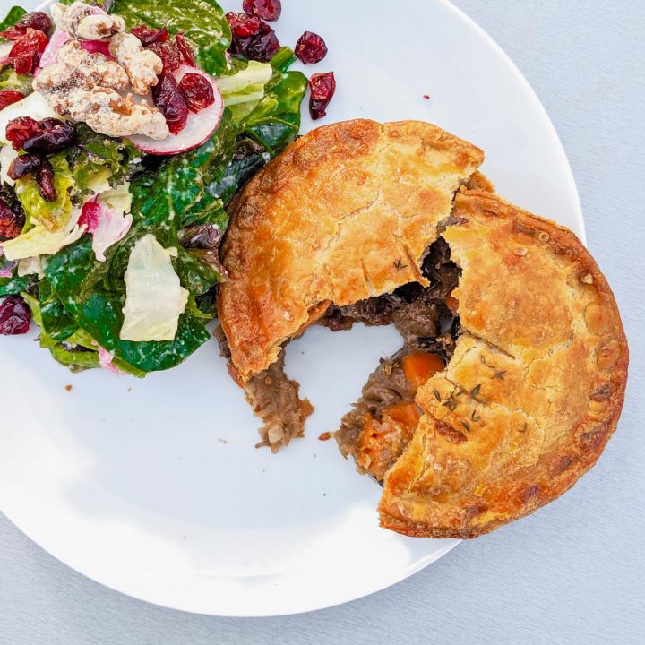 Steak and mushroom pie recipe on a plate with a green salad.