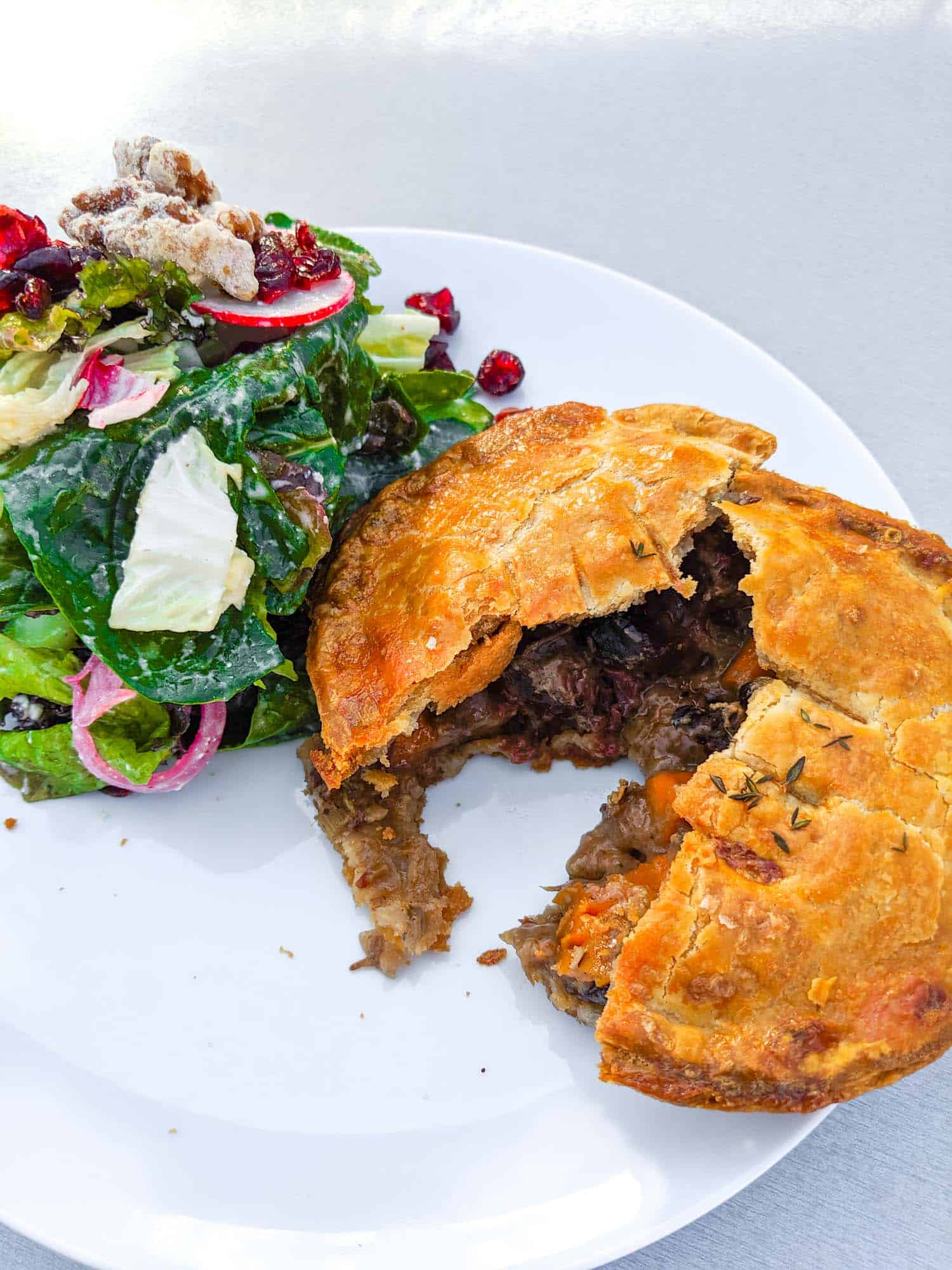 Steak and mushroom pie recipe on a plate with a green salad.