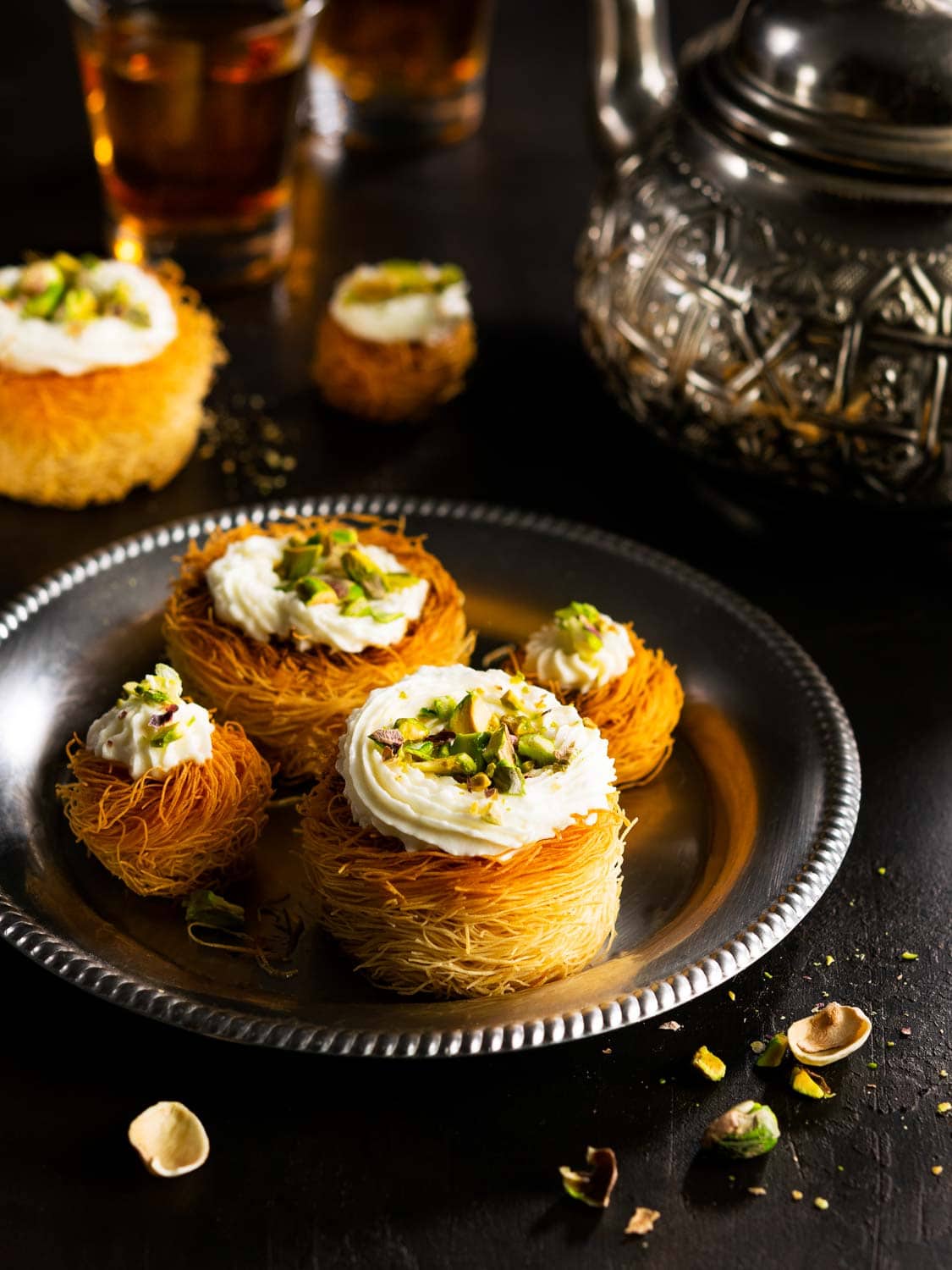 Kataifi, kadayif, kunafa, baklava pastry nests cookies with pistachios with tea. Cooking sweets turkish, or arabic traditional ramadan pastry dessert on a dark background.