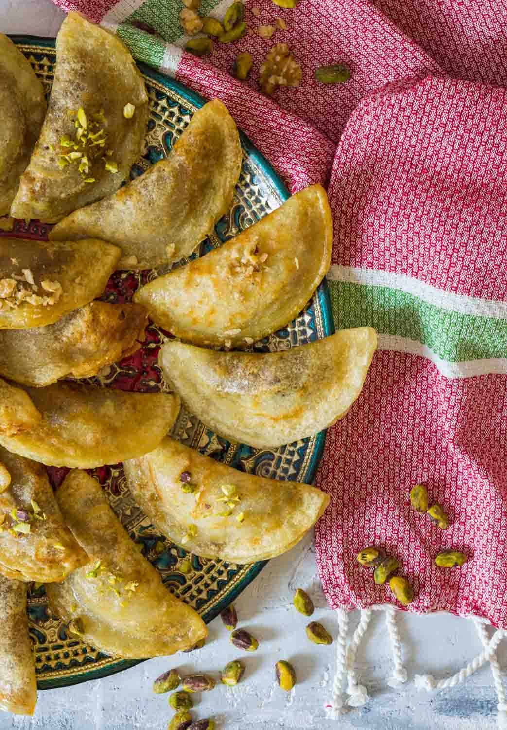 Arabic Traditional dessert Qatayef or Atayef served with sugar and rose syrup and roasted nuts. 