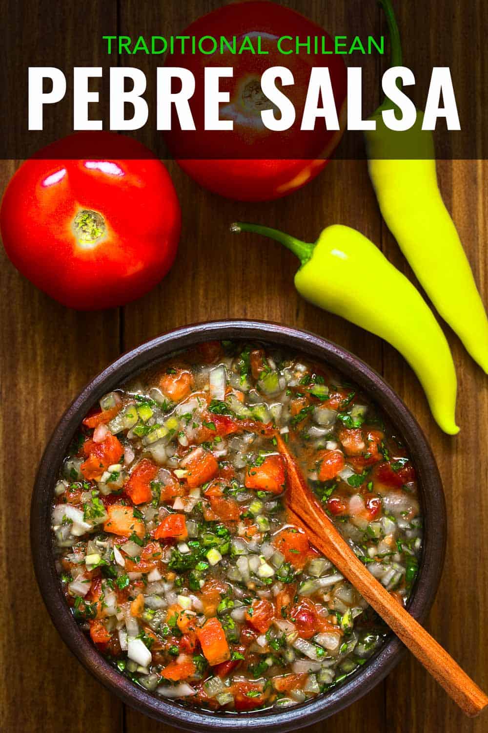 Bowl of cilantro salsa on a table with tomatoes and aji peppers