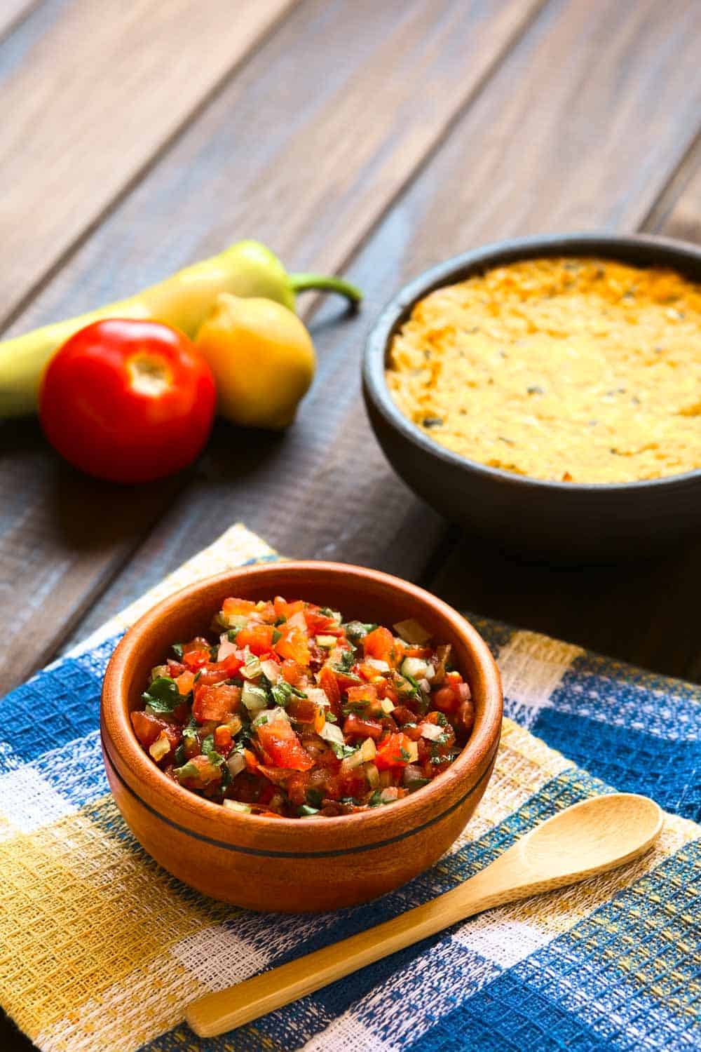 Traditional Chilean sauce made of tomato onion aji verde (small green hot pepper) lemon juice and coriander leaves served for barbecue and traditional dishes photographed on wood with natural light (Selective Focus Focus in the middle of the pebre)