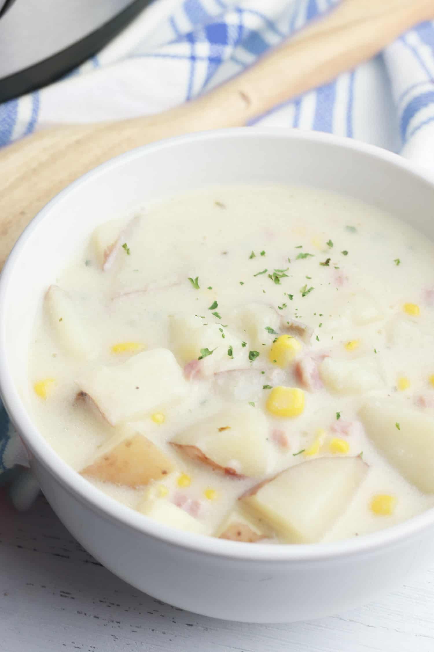 Creamy corn soup in a white bowl in a kitchen.