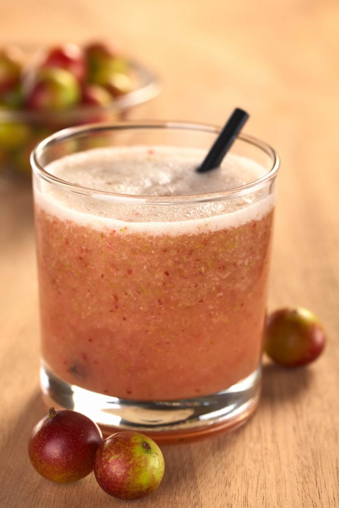 Juice out of Camu camu berry fruits from Peru (lat. Myrciaria dubia) which are grown in the Amazon region and have a very high Vitamin C content (Selective Focus Focus on the front rim of the glass)