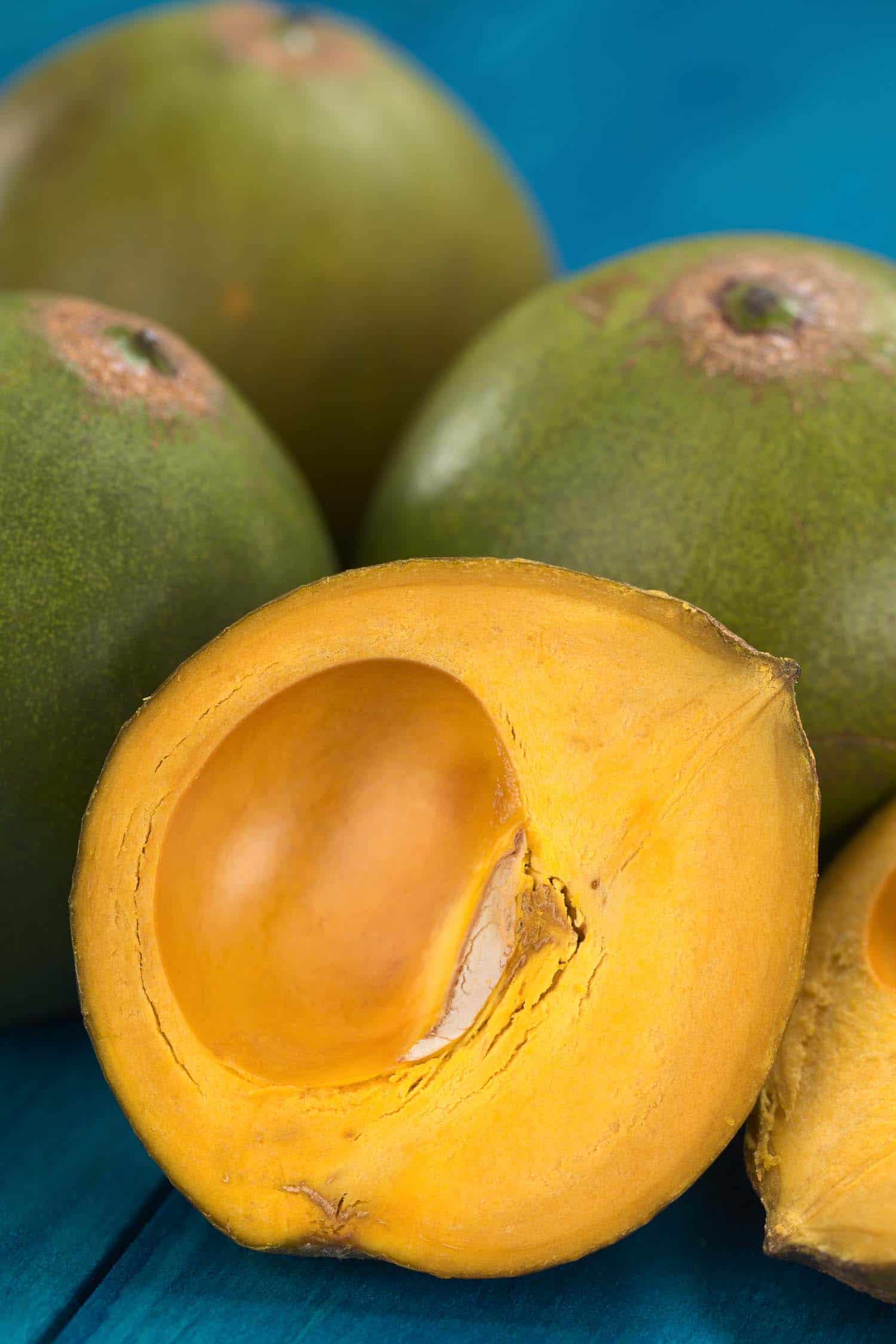 Peru fruit called Lucuma (lat. Pouteria lucuma) which has a dry sweet flesh and is mostly used to prepare juices milkshakes yogurts ice cream and other desserts (Selective Focus Focus on the front of the standing lucuma half)