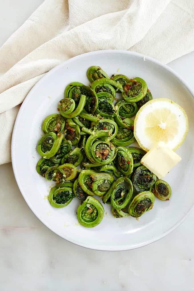 Fiddleheads sauteed in garlic butter on a white background