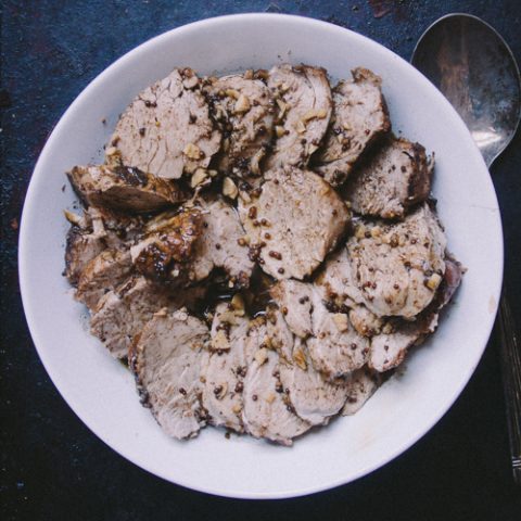 pork tenderloin sliced on a white plate on a blue background