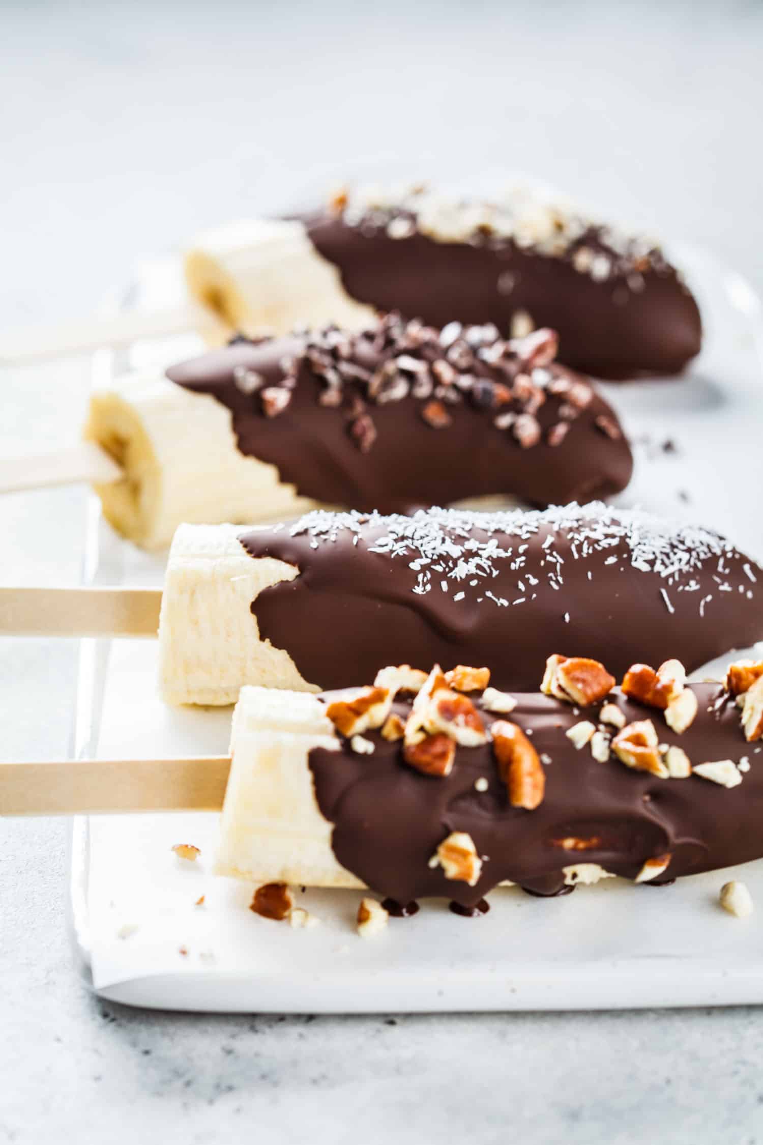 Chocolate covered bananas on a tray also called chocobananos or monkey tails.