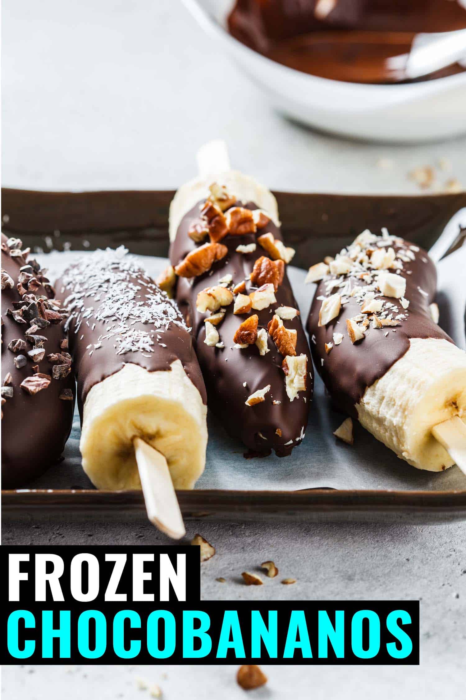 Chocobanano or chocolate covered bananas on a tray covered in nuts and chocolate