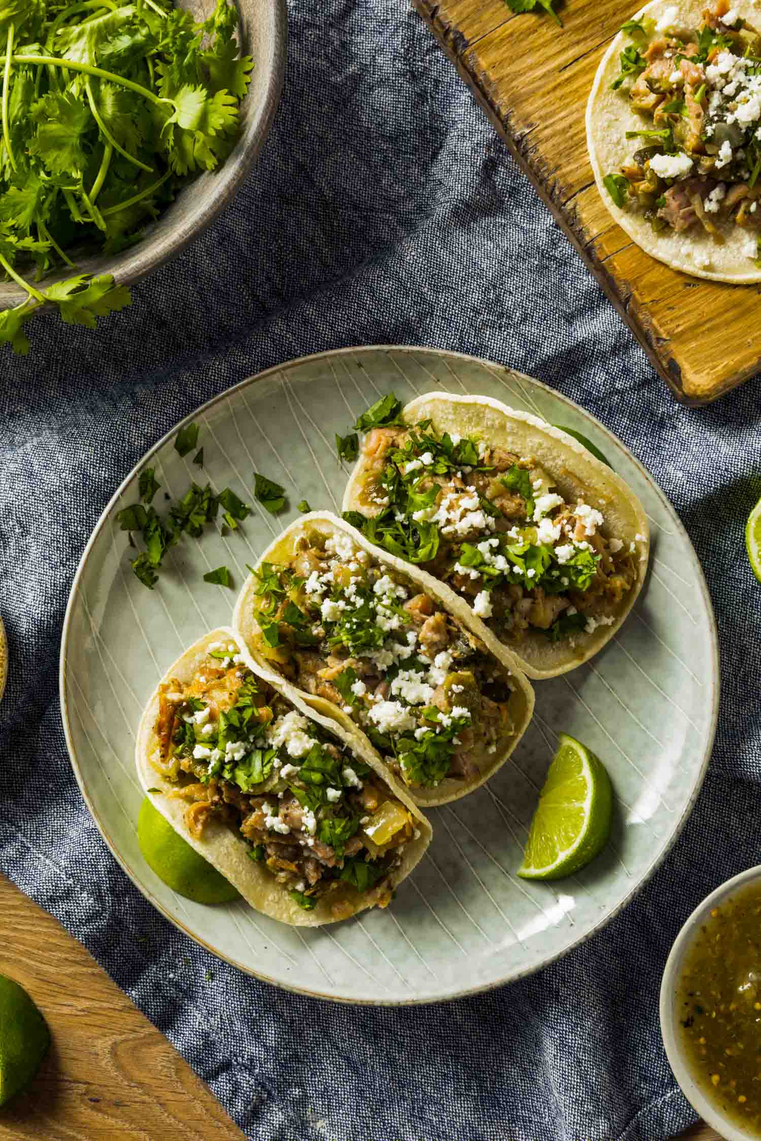 Pork carnitas tacos on a plate with cilantro and lime