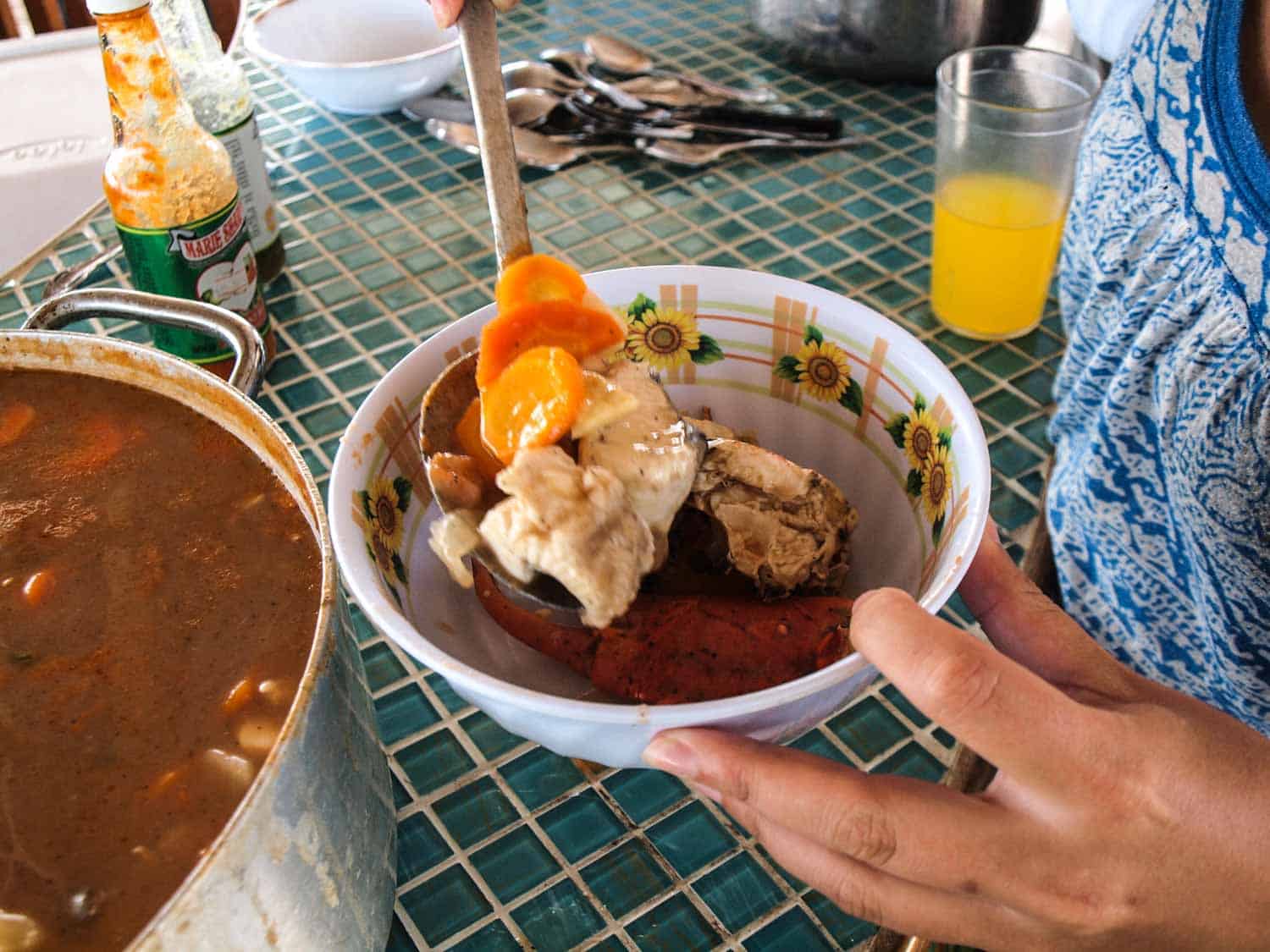 Belize caldo in pot being poured into a bowl.