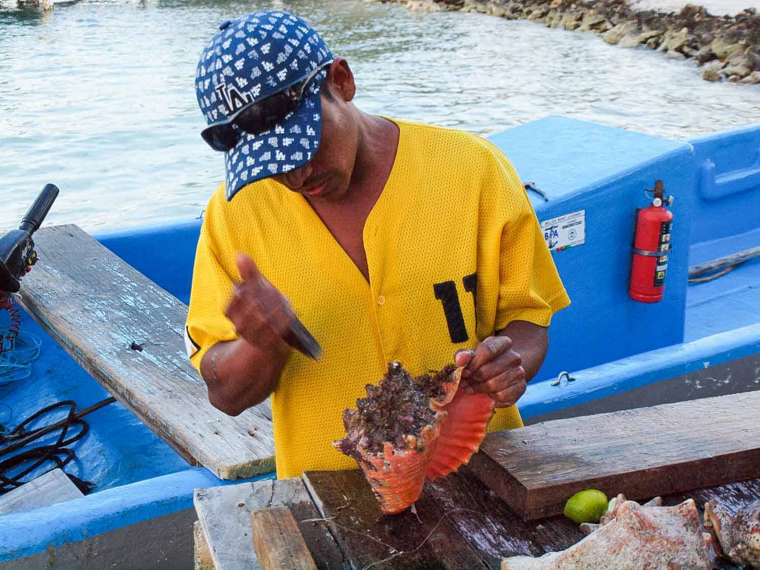 Man extracting conch in Belize to make soup
