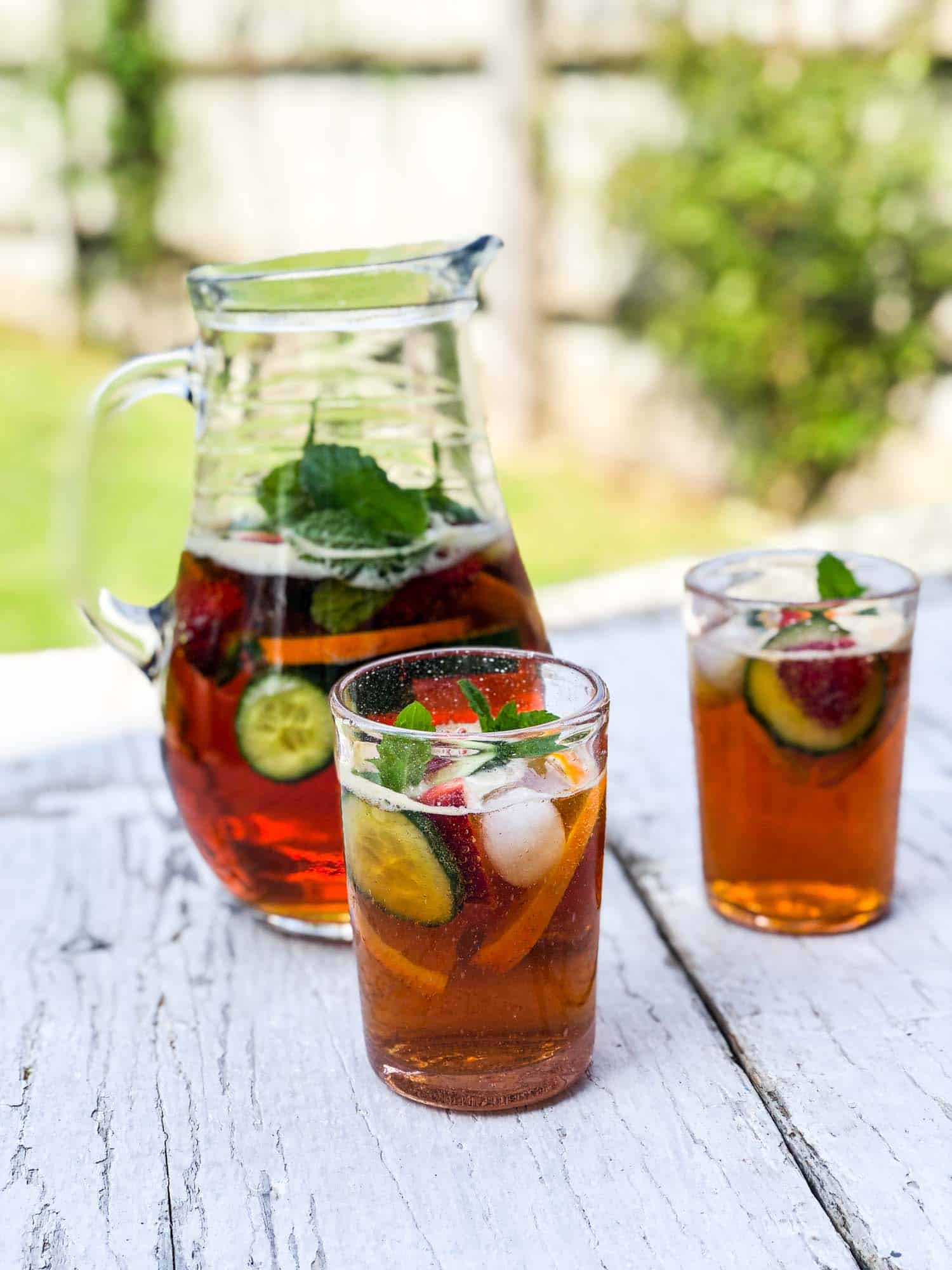 A pitcher of Pimm's with two glasses on a table.