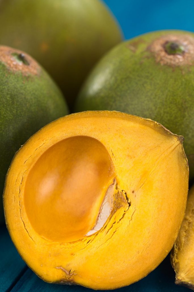 Hawaiian fruit called eggfruit, also known in Peru as lucuma (lat. Pouteria lucuma) which has a dry sweet flesh and is mostly used to prepare juices milkshakes yogurts ice cream and other desserts (Selective Focus Focus on the front of the standing lucuma half)