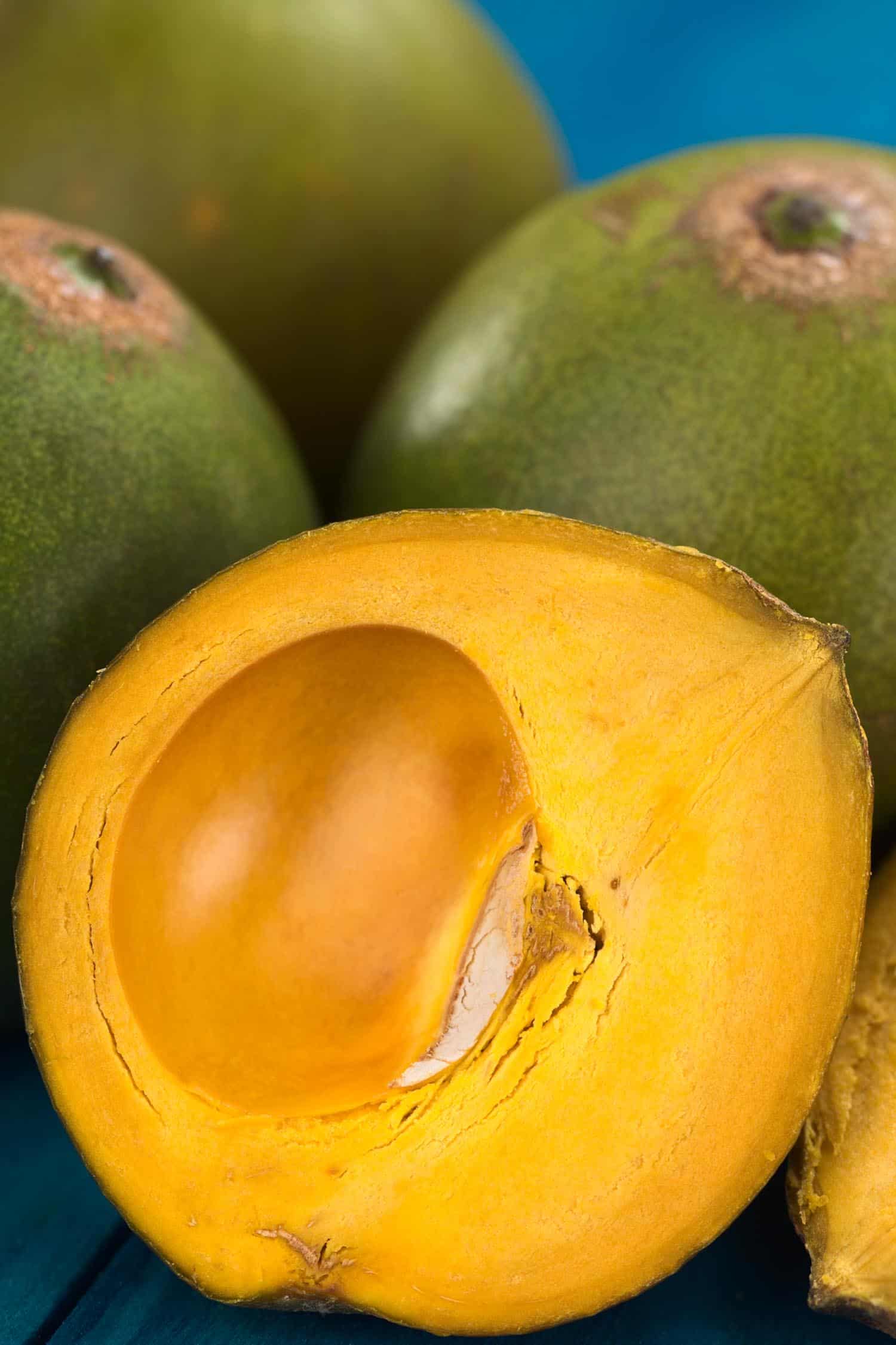 Hawaiian fruit called eggfruit, also known in Peru as lucuma (lat. Pouteria lucuma) which has a dry sweet flesh and is mostly used to prepare juices milkshakes yogurts ice cream and other desserts (Selective Focus Focus on the front of the standing lucuma half)
