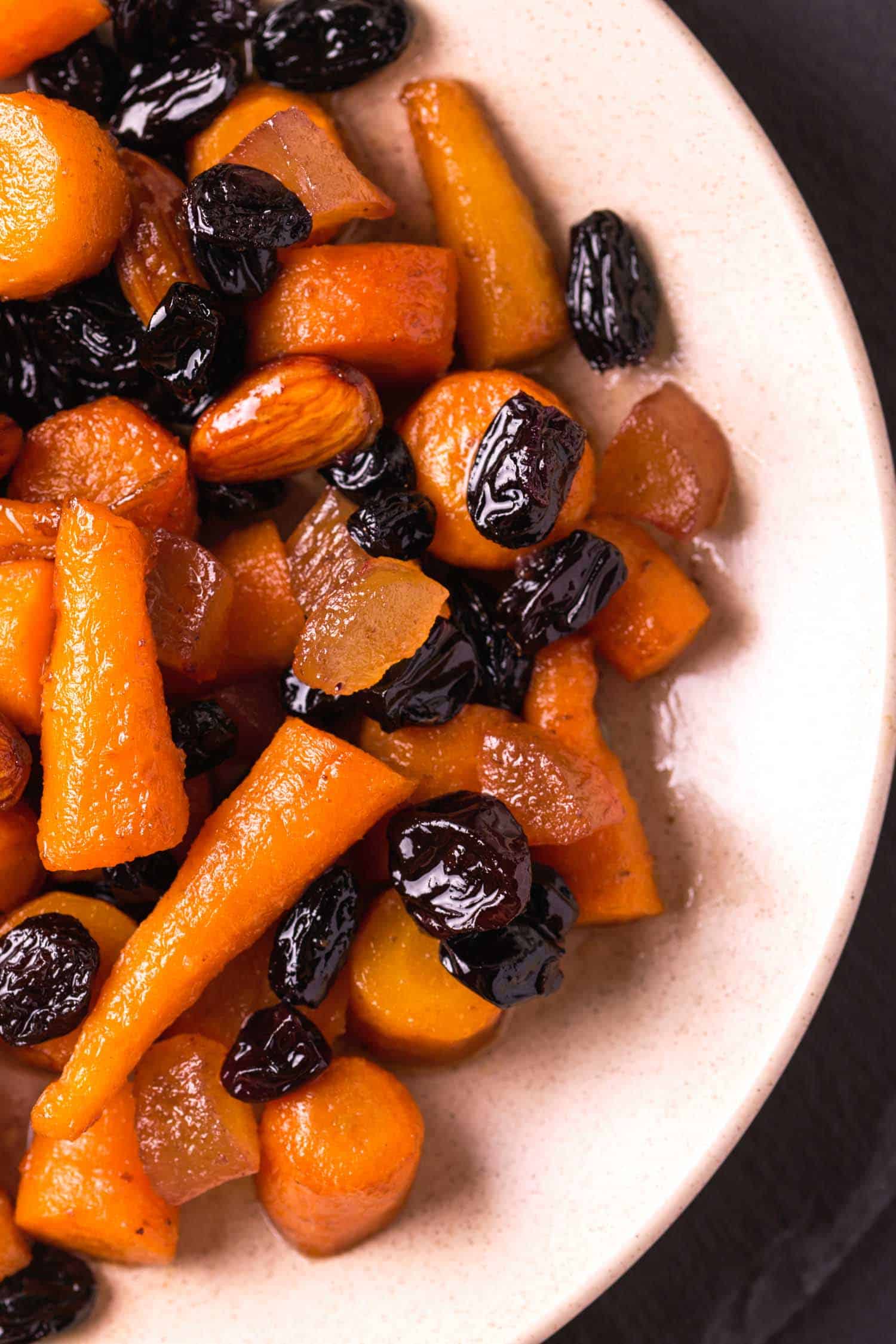 Tzimmes or carrots and dried fruits on a white plate