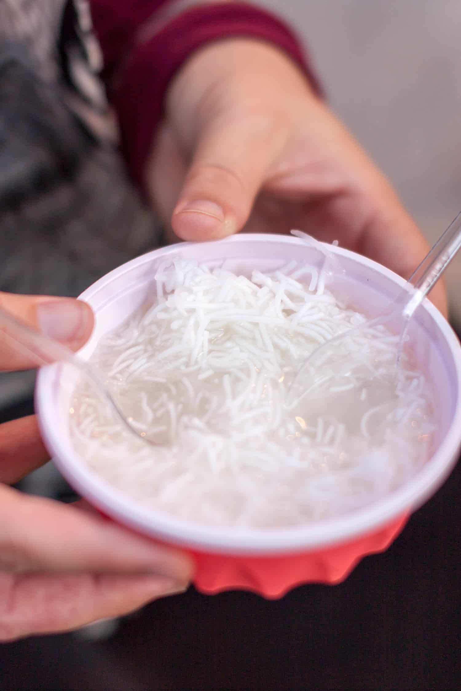 Faloodeh in a bowl, a common Nowruz food dessert, held in a plastic red bowl.