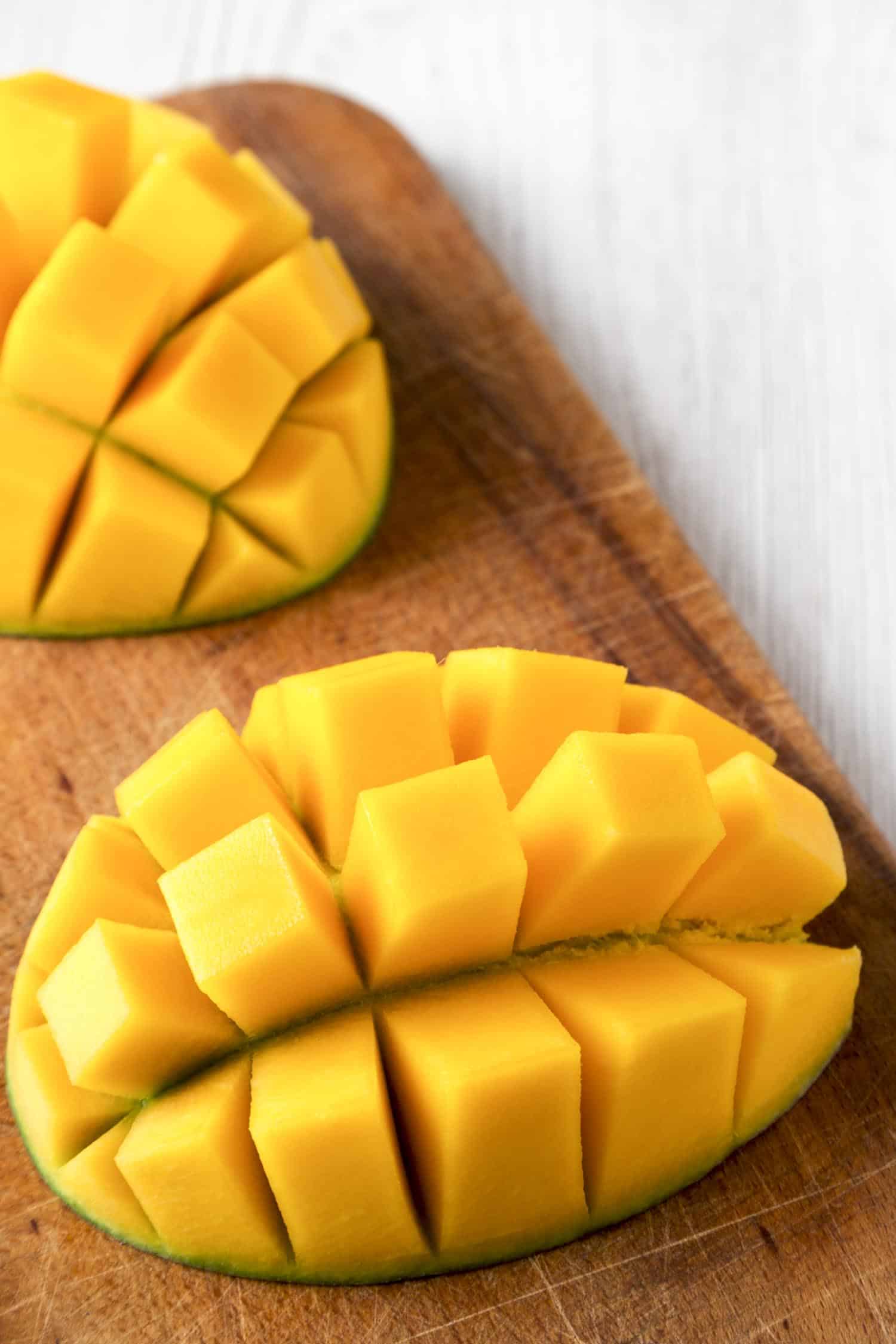 Fruit in Hawaii, sweet mango on rustic wooden board on a white wooden table, low angle view.