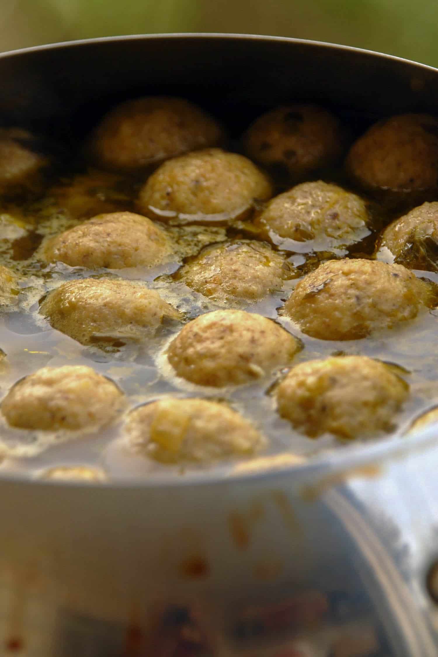 matzah ball soup in a pan simmering, common Rosh Hashanah food