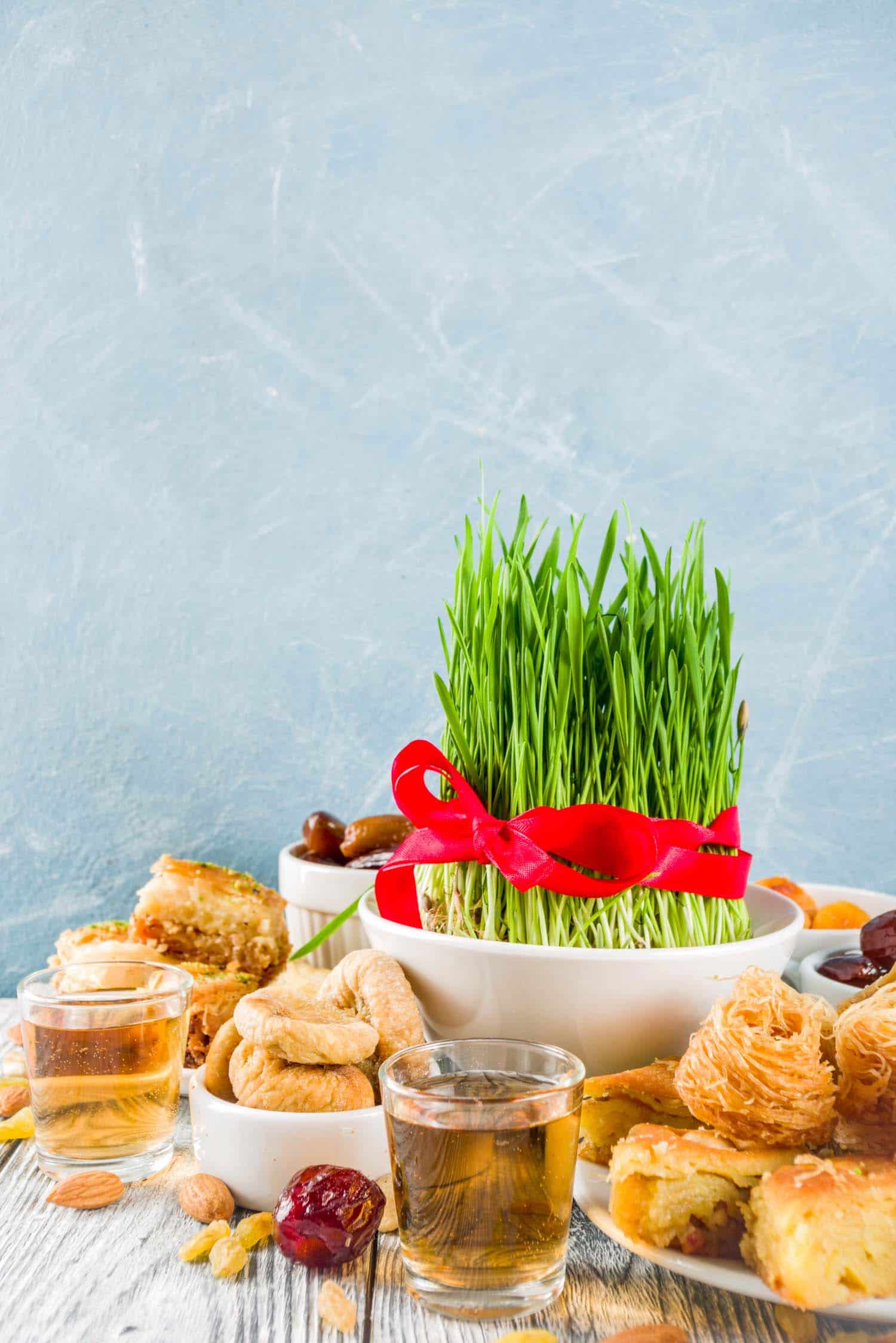 Table full of Persian food for Nowruz including Persian desserts and wheat germ.