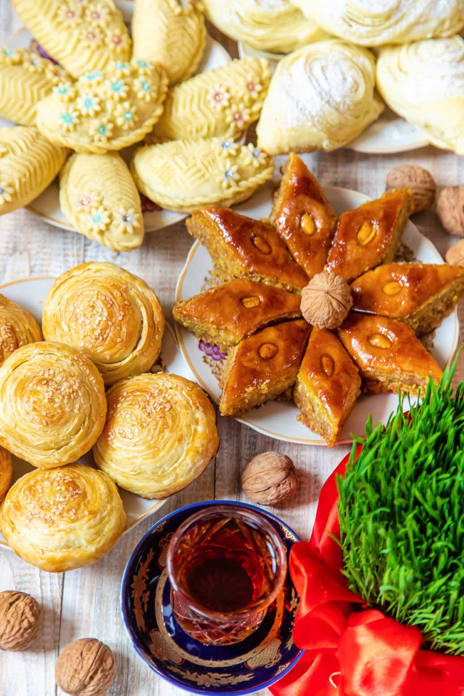 Table full of Persian food for Nowruz including Persian desserts and pastries and wheat germ.